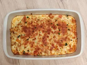 Zapečená rýže v bílém pekáči s žlutou omáčkou a bylinkami.