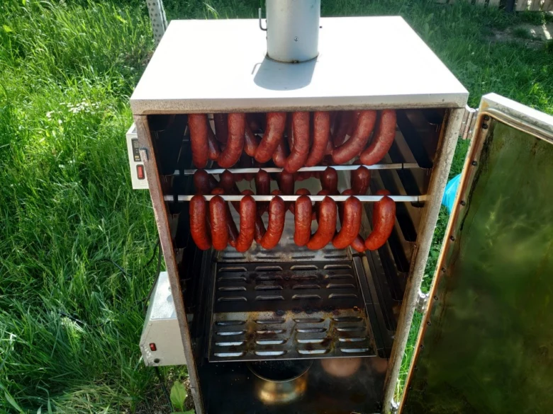 Klobásy se kouří v venkovním dýmovací troubě.