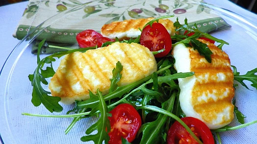 Grilovaný sýr halloumi na salátu se špenátem a rajčaty.