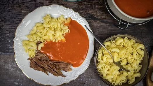 Palačka s makarony, masem a omáčkou na talíři.