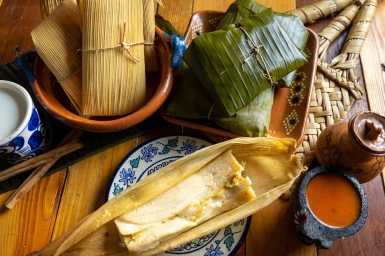 Tradiční mexické tamale s omáčkou na dřevěném stole.