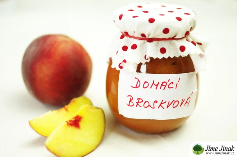 Sklenice domácí broskvové marmelády s čerstvými broskvemi.