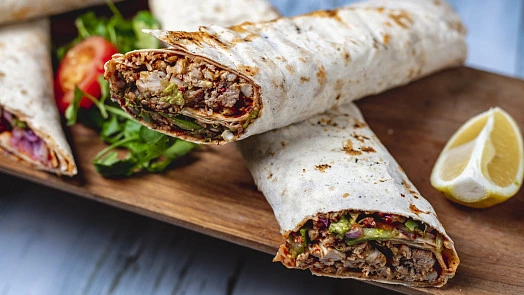 Domácí kebab s masem a zeleninou na dřevěném talíři.