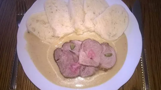 Přesnídka s vepřovou kýtou a omáčkou na bílém talíři.
