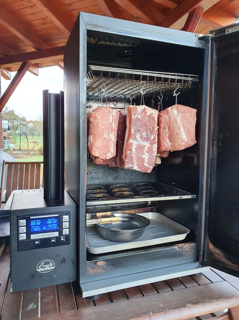 Digitální kuřák s visícím hovězím masem na dřevěné terase.