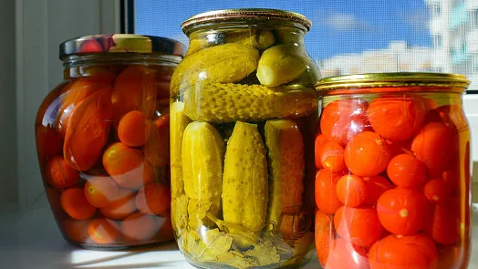 Sklenice s okurkami a rajčaty po sterilizaci v troubě.