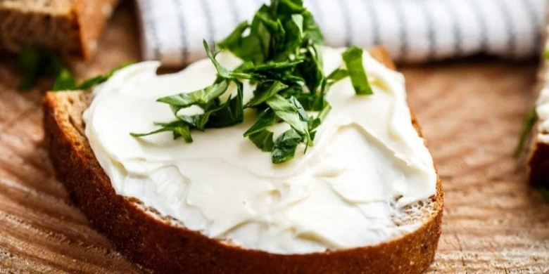 Kousek chleba s bílým náhradou pro mascarpone a bazalkou