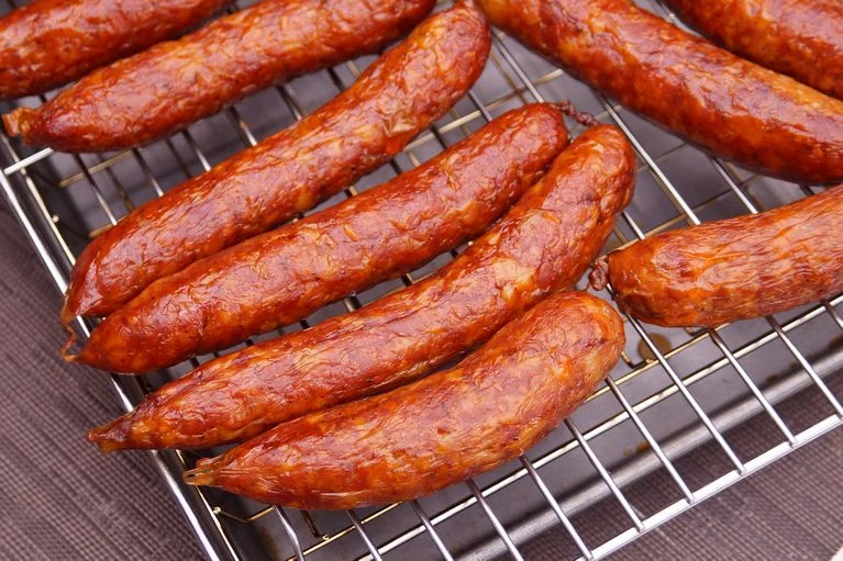 Domácí klobásy upečené na mřížce s lesklou povrchovou úpravou.