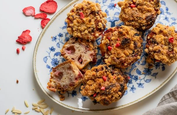 Zlaté muffiny s jahodami a křupavým vrchním nálevem na talíři.
