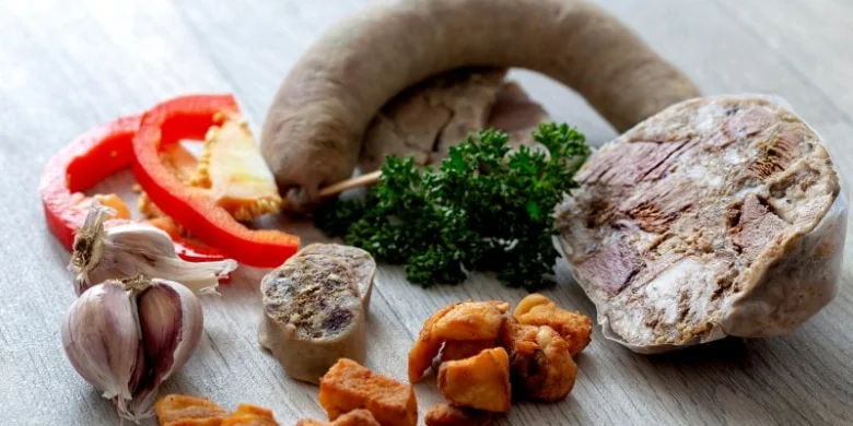 Suroviny pro zavařování masa: maso, klobásy, česnek a zelenina.