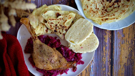 Pečená kachna s červenou řepou a chlebem na talíři.