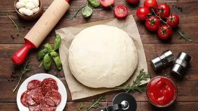 Kulová těsto na pizzu s ingrediencemi jako bazalka, rajčata a šunka