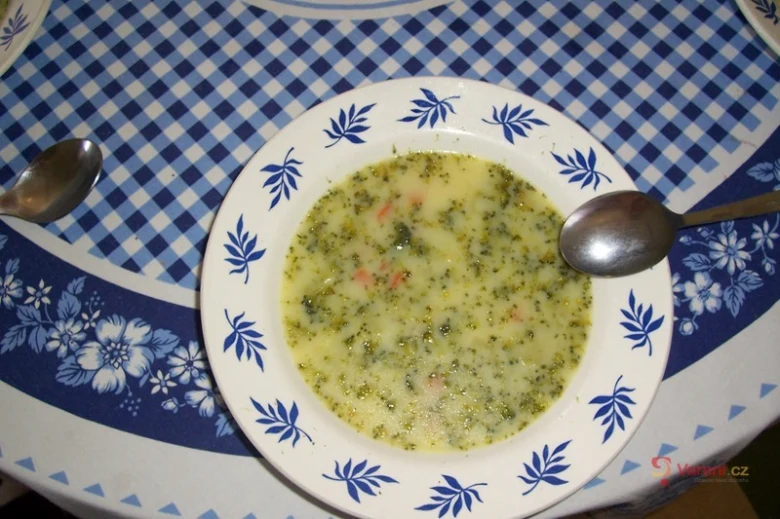 Bílá brokolicová polévka v misce na modro-bílém ubrusu.