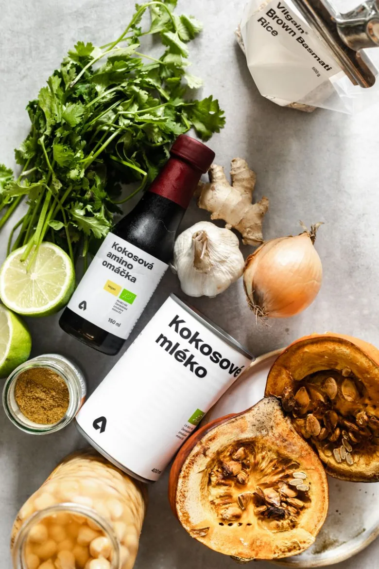 Ingredience pro dýňové kari s kokosovým mlékem na světlém povrchu.