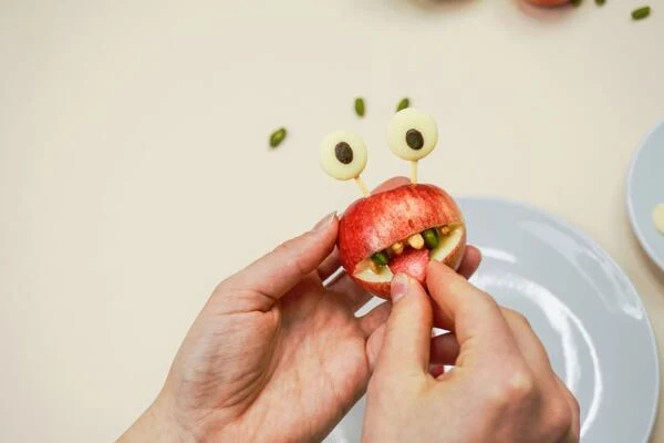 Ruce tvoří zdravé jablkové jídlo pro děti s přirozenými ingrediencemi.