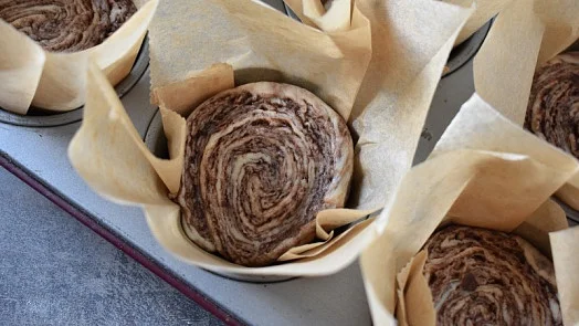 Nepečené muffiny s čokoládou v papírových formách na plechu.