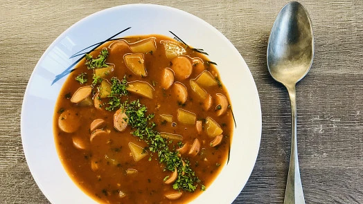 Bílá miska s tradiční polévkou z špekáčku a zeleniny.