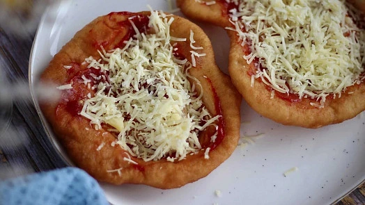 Uncooked langos with cheese and sauce