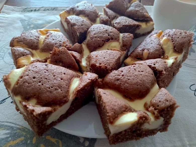 Domácí čokoládové cheesecake tyčinky s bílým tvarohovým náplní na talíři.