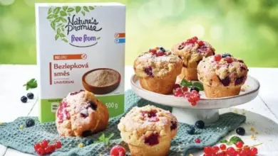 Krabička bezlepkové směsi vedle čerstvých muffinů s bobulemi.