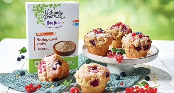 Krabička bezlepkové směsi vedle čerstvých muffinů s bobulemi.