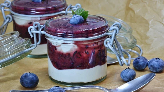Sklenice s vrstveným dezertem z tvarohu a borůvkami.