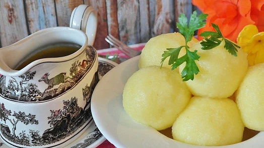 Knedlíky s omáčkou na talíři vedle podlévky.